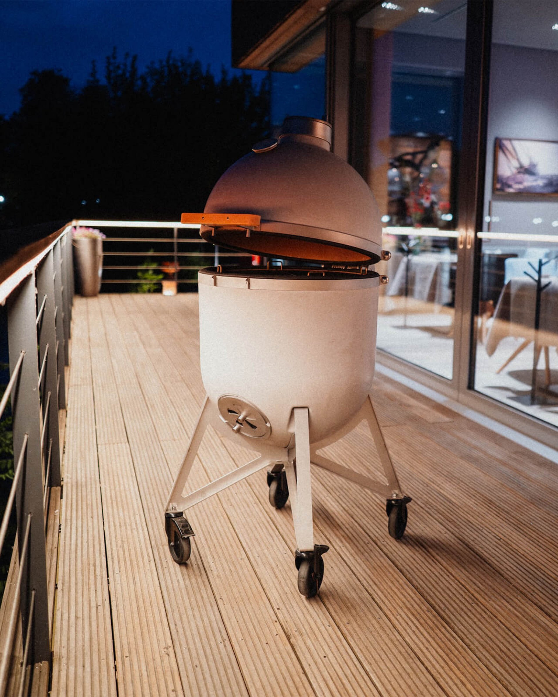 Compadre concrete grill with an open lid on a wooden terrace in the evening light